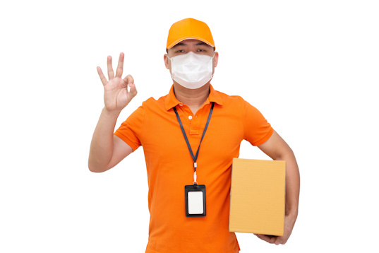 Delivery man holding parcel box and wearing protective mask for prevent virus Covid-19 and showing ok isolated on white background, Online shopping shipment and fast express delivery service concept