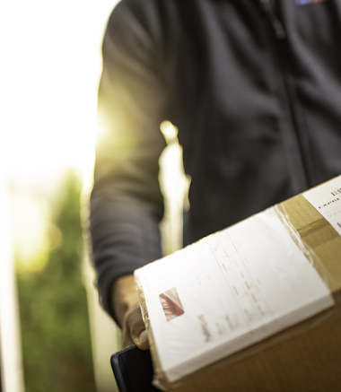 Close up of an unrecognisable courier holding cardboard box prepared for home delivery.